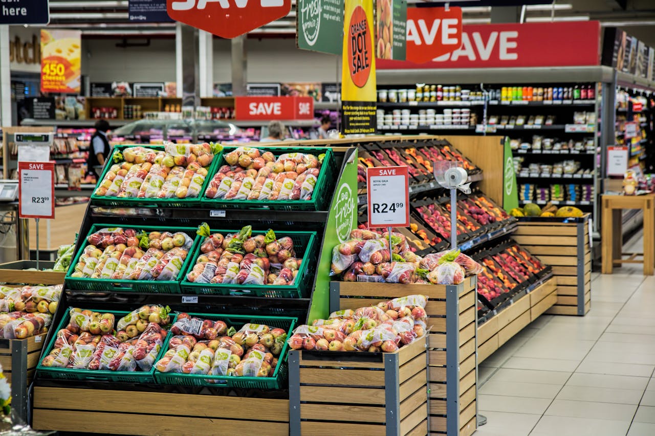 about-us Colorful produce aisle in a supermarket showcasing fresh apples with discount signage.